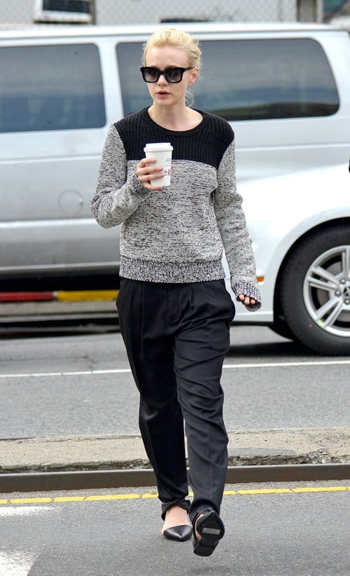 Carey Mulligan wears pajama pants with a two-tone wool sweater, square sunglasses, and bow flats