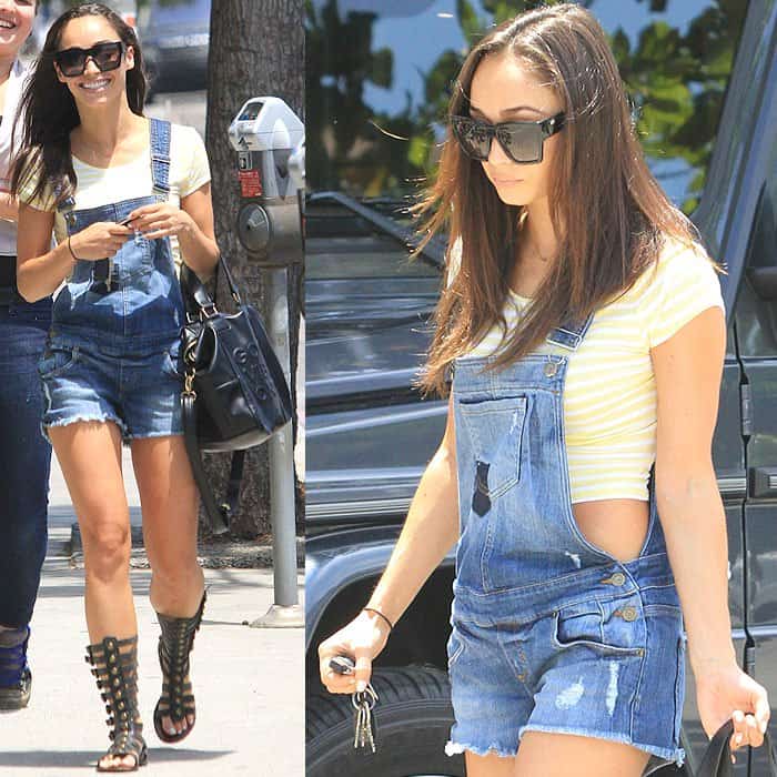 Cara Santana wearing a yellow crop tee, short overalls, and gladiator sandals, and carrying a BCBGeneration "Good Vibes Only" handbag