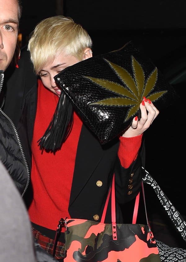 Miley Cyrus totes a marijuana leaf-embellished snakeskin clutch purse by Jacquie Aiche