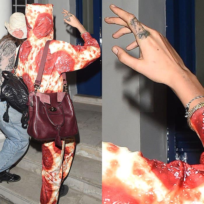 Cara Delevingne holding up her hand with the lion finger tattoo