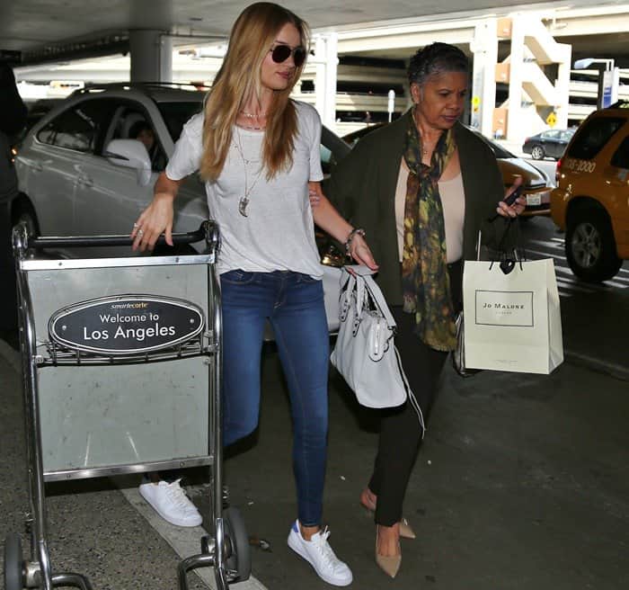 Rosie Huntington-Whiteley pushing an airport trolley with shopping bags as she arrives from a flight